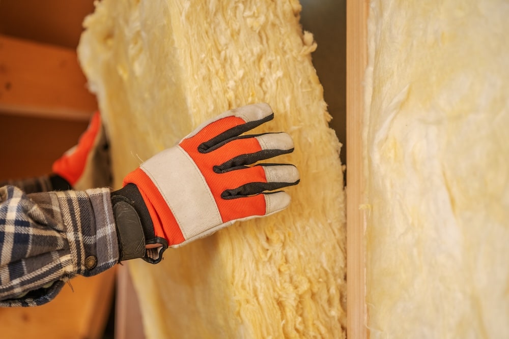 Worker installing fiberglass insulation batts